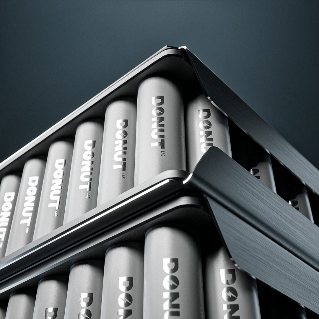 Close-up of two stacks of cylindrical batteries labeled "DONUT." The batteries are neatly arranged in two metallic trays, one on top of the other, at an angle. The background is a dark gradient.
