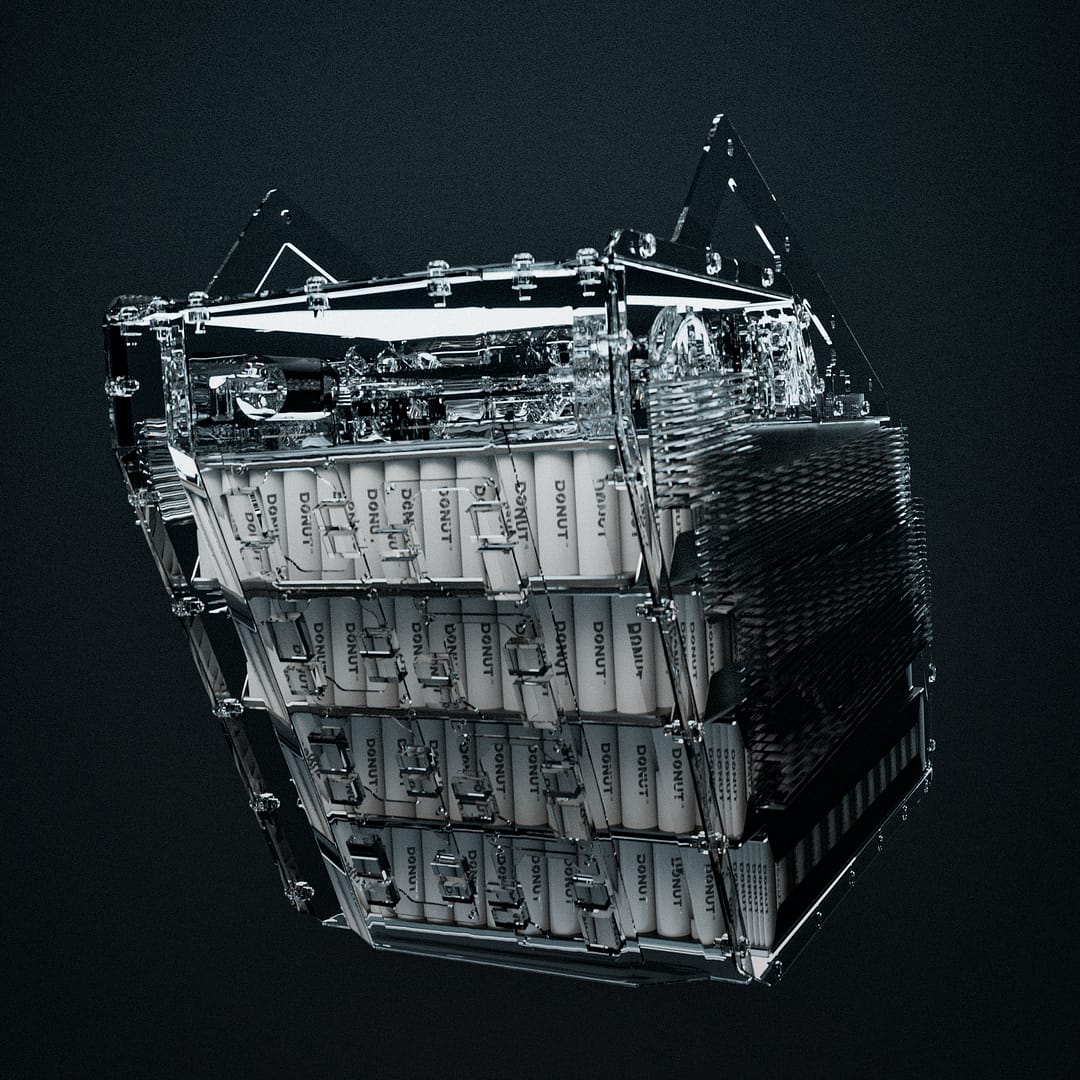 A complex, metallic cube-like structure with various mechanical parts, wires, and textured surfaces, set against a dark background. It features rows of white rectangular modules labeled "DO NOT DROP.