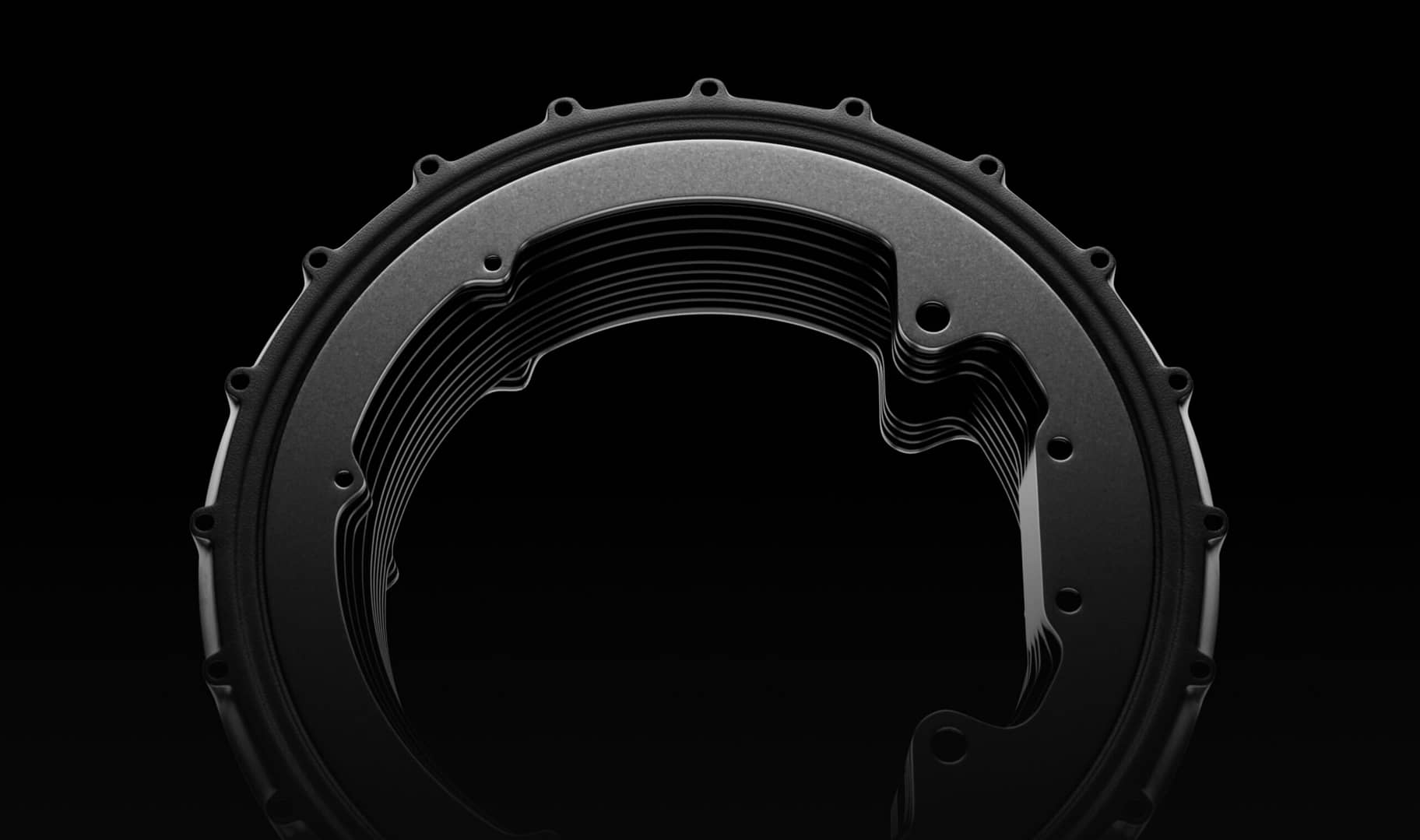 Close-up of a circular, metallic component with a layered design against a black background. The object features a series of evenly spaced holes along its outer edge and a smooth, reflective surface, giving it an intricate, industrial appearance.