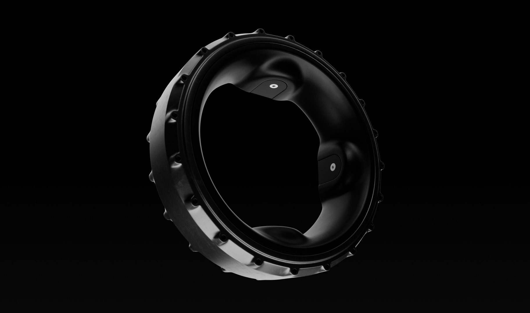 A sleek, black, circular object with a glossy finish, featuring a toothed outer edge and an open center. It is set against a dark background, creating a striking contrast.