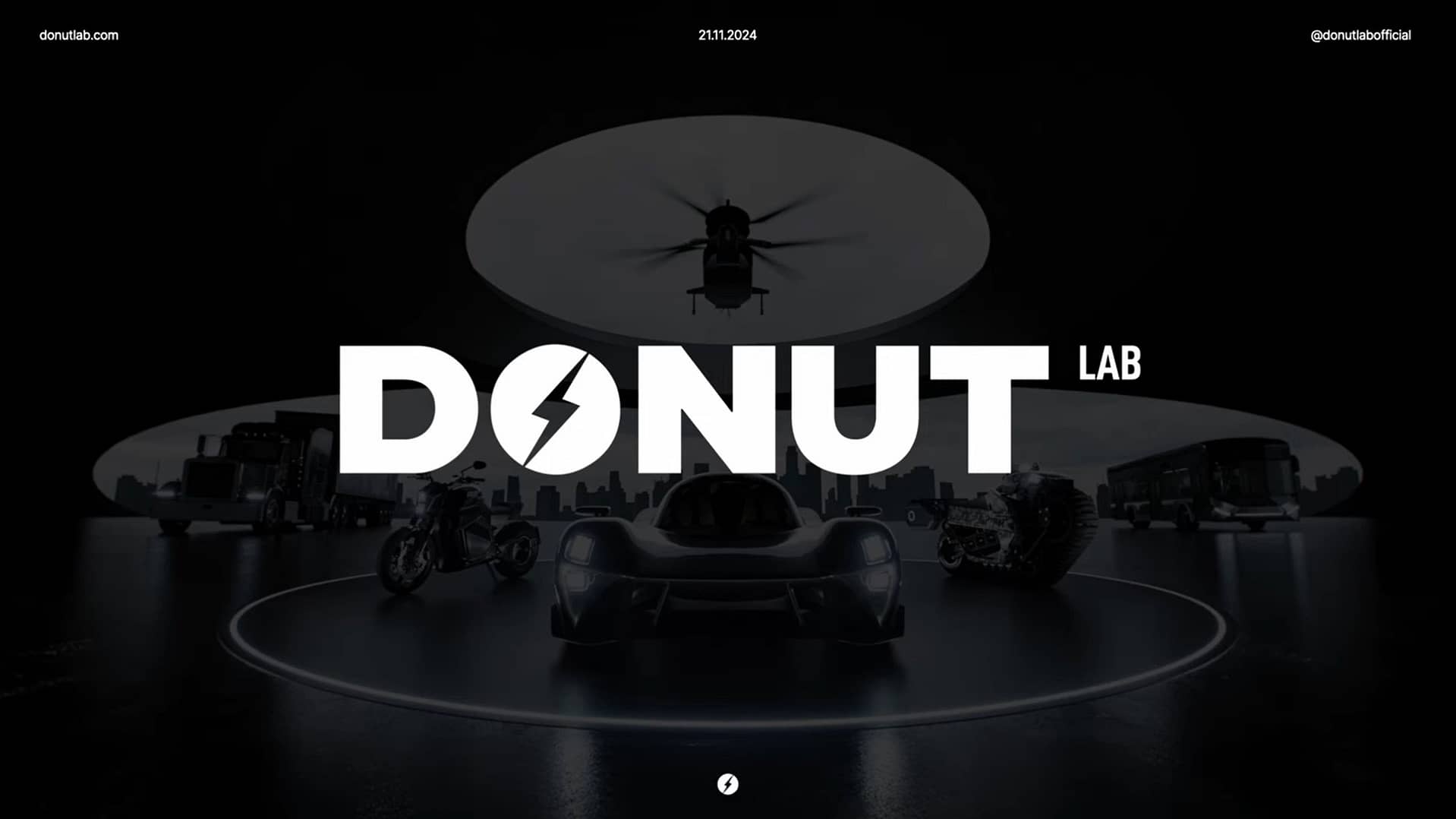 Dark futuristic laboratory with 'DONUT LAB' in bold white letters. Silhouettes of a car, two motorcycles, a drone, and a futuristic vehicle are set against a city skyline. Twitter handle and website URL are shown at the top.