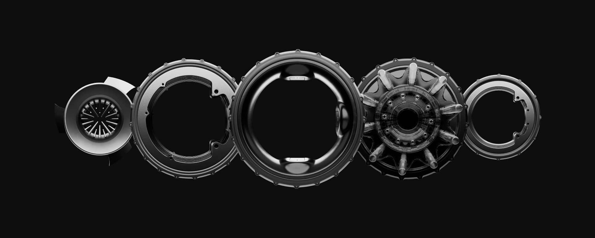 Five mechanical components arranged in a row on a black background, showcasing a variety of intricate shapes and textures. The parts resemble housings and gears, each with distinct circular designs and cut-outs.