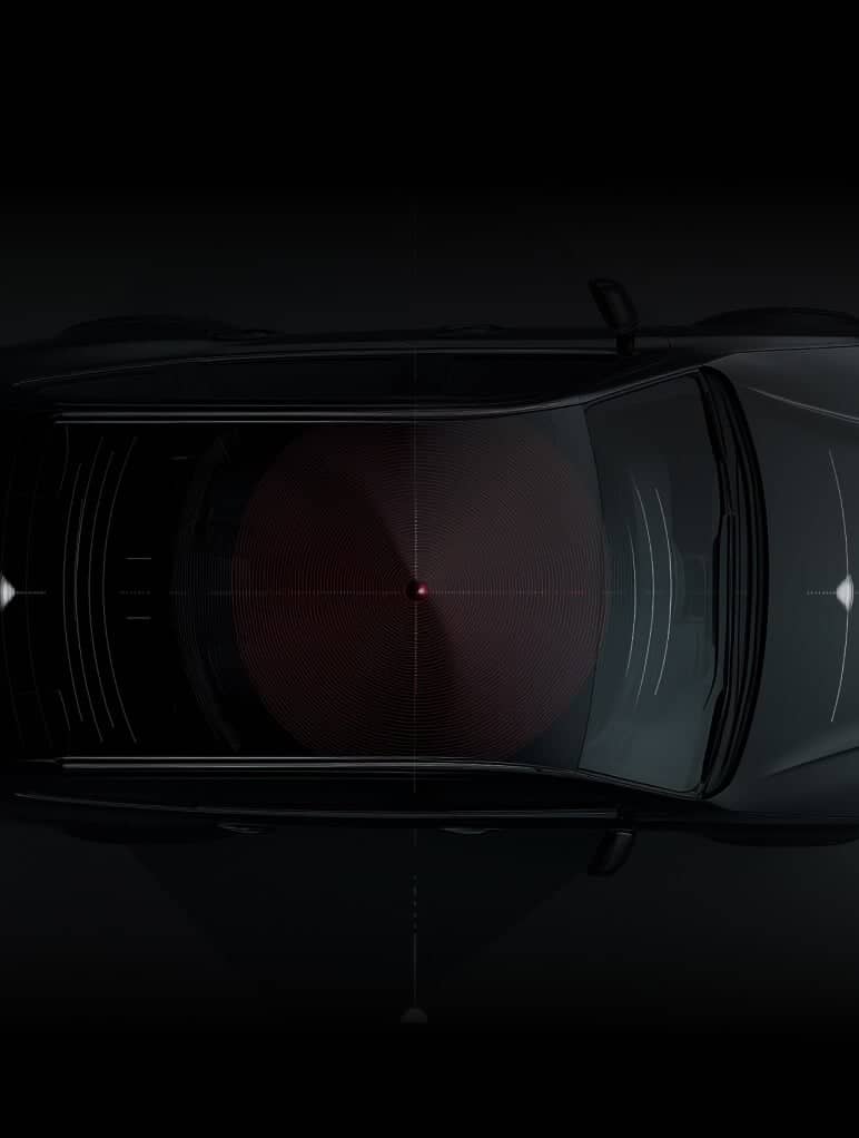 Top view of a car in low light, showing a radar or sensor system visualized as circular patterns emanating from the center. The vehicle is sleek and dark, with emphasis on the technology.