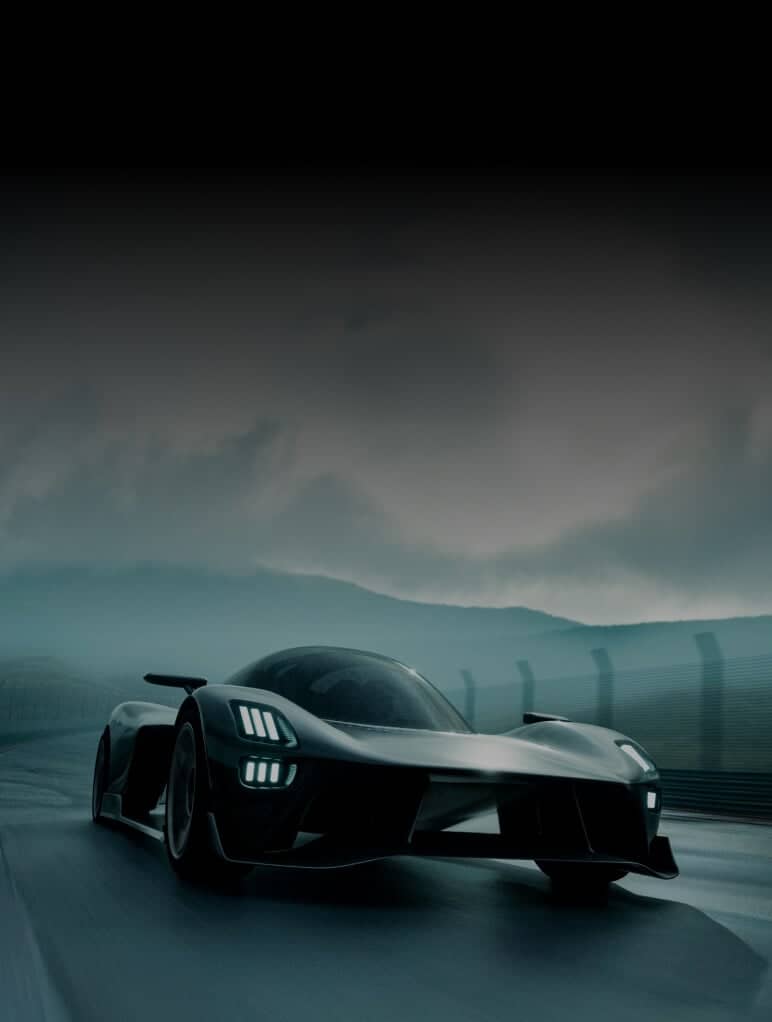 A sleek, futuristic black sports car speeds along a racetrack under a moody, overcast sky. The car's aerodynamic design and glowing headlights contrast with the blurred background, emphasizing its motion and high-performance capabilities.
